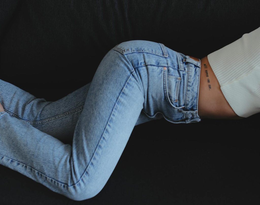 crop female in jeans on black background